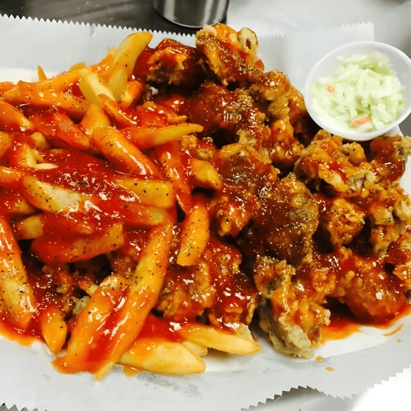 Harold's 25 fried chicken and french fries, both covered in a sweet and spicy sauce, with a side of coleslaw.