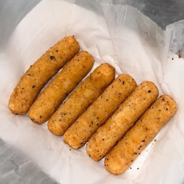 Six golden-brown fried mozzarella sticks with herbs, served in a white paper-lined basket.