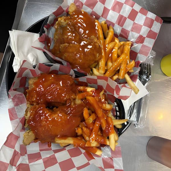 Two baskets of Harold's 25 fried chicken and fries, both drenched in a sweet and spicy sauce.