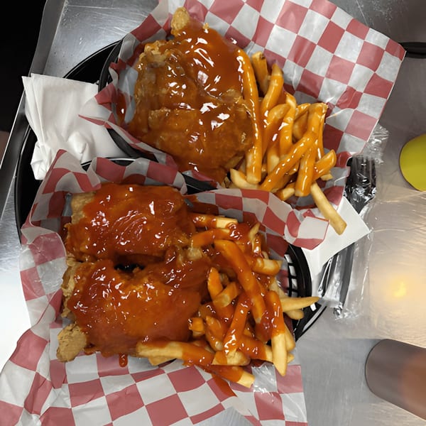 Two baskets of Harold's 25 fried chicken and fries, both covered in a sweet and spicy sauce.